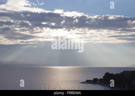 I raggi del sole illuminano il mare Adriatico. Silhouette della costa. Foto Stock