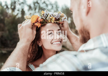 Bella e verde-eyed sentimento donna estremamente felice la ricezione di Nizza coroncina floreale Foto Stock