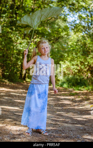 Bella ragazza caucasica con verde bardana pianta nel verde della foresta Foto Stock