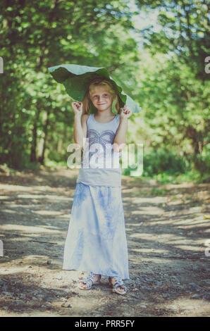 Bella ragazza caucasica con verde bardana pianta nel verde della foresta Foto Stock