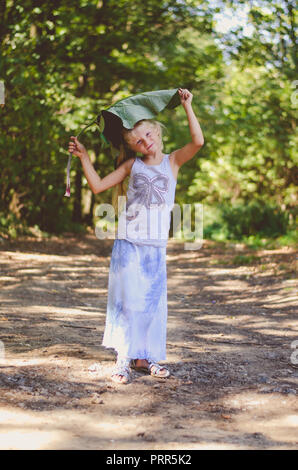 Bella ragazza caucasica con verde bardana pianta nel verde della foresta Foto Stock