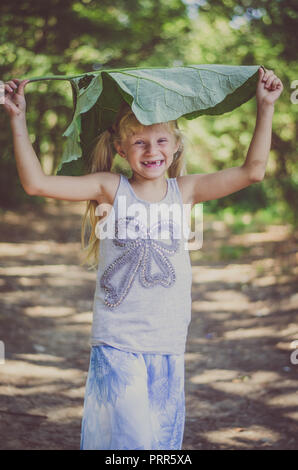 Bella ragazza caucasica con verde bardana pianta nel verde della foresta Foto Stock