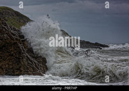 Onde infrangersi contro le rocce da Mumbles faro nel bracciale Bay, Swansea, Wales, Regno Unito Foto Stock