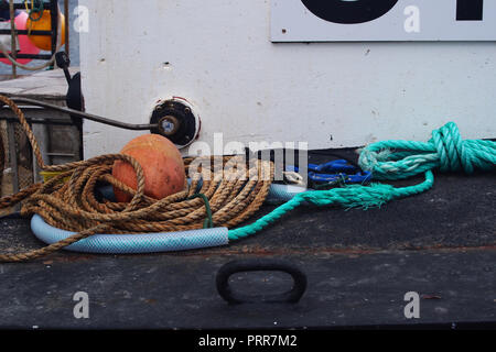 Varie corde galleggianti e attrezzi da pesca steso sul ponte di una piccola barca da pesca Foto Stock