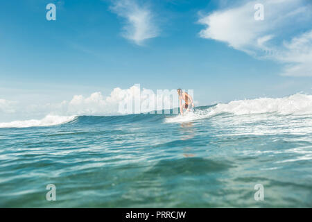 Vista in lontananza sportivo maschio surf in oceano presso la spiaggia di Nusa Dua, Bali, Indonesia Foto Stock