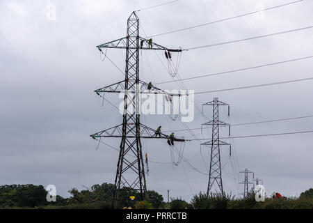 Lavoratori di elettricità che indossa cavi di sicurezza su un traliccio di elettricità nel processo di sostituzione dei cavi alta tensione Foto Stock