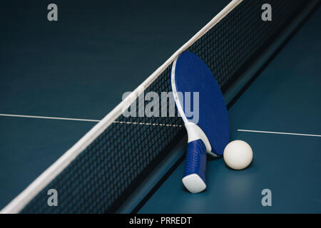 Tabella racchette da tennis e la sfera e la rete su un blu tavolo da ping pong Foto Stock