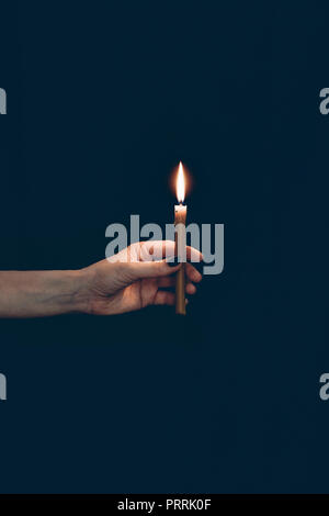 Vista parziale della ragazza con candela fiammeggiante isolato su nero Foto Stock