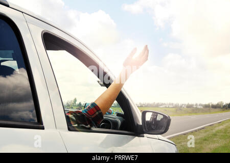 Donna sticking braccio fuori la finestra auto su roadtrip. Femmina lato conducente la sensazione di aria e libertà. Foto Stock