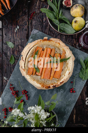 Vista in elevazione del cotto golosa torta con le carote e le erbe sul tavolo di legno Foto Stock