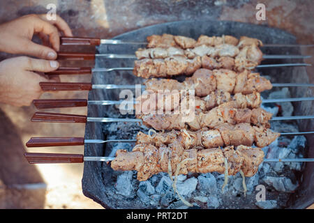 La carne cruda è fritto al rogo. Maschio di friggere gli spiedini sulla griglia Foto Stock