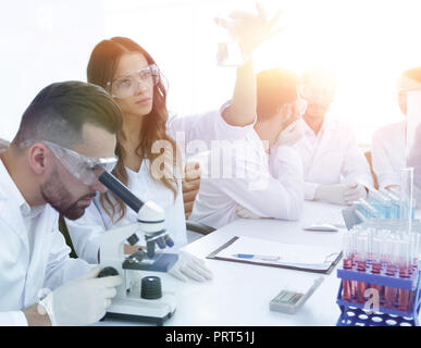 Gli scienziati di esaminare attentamente la pipetta con fluido blu in laboratorio Foto Stock