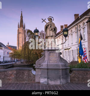 Statua di San Joannes Nepomucenus, con la Chiesa di Nostra Signora della torre di Bruges in background, città medievale di Bruges (Brugge), Belgio Foto Stock