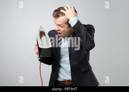 Unione uomo maturo in tuta azienda ferro elettrico con sporco bruciato spot Foto Stock