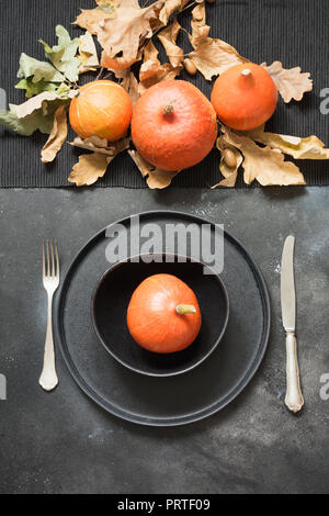 La Giornata del Ringraziamento o di Halloween luogo impostazione con zucca arancione sulla tavola nera. Vista dall'alto. Foto Stock