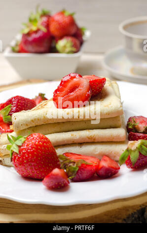 Sottile di fresco frittelle con le fragole sulla piastra bianca. Foto Stock