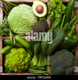 Assortiti nei toni del verde materie biologica di verdure in scatola in legno sulla pietra scura sullo sfondo. Avocado, Cavoli, cavolfiori e cetriolo con rifilato e mung b Foto Stock