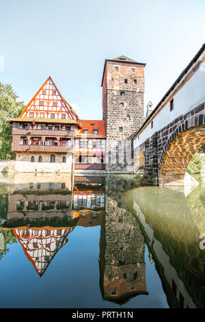 Bellissima vista del paesaggio lungo il fiume con la vecchia torre e la casa con la riflessione a Nurnberg durante il Sunrise, Germania Foto Stock