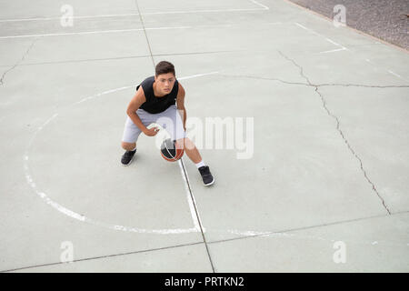 Un adolescente di sesso maschile del giocatore di basket la pratica sul campo di pallacanestro, ad alto angolo di visione Foto Stock