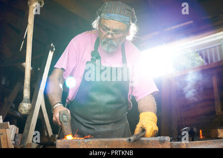 Fabbro lavora nella sua fucina Foto Stock