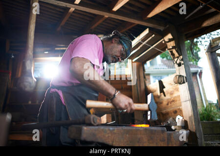 Fabbro lavora nella sua fucina Foto Stock