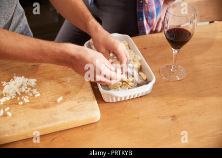 Paio di mettere le verdure nella tostatura piatto sul tavolo da cucina, close up delle mani Foto Stock