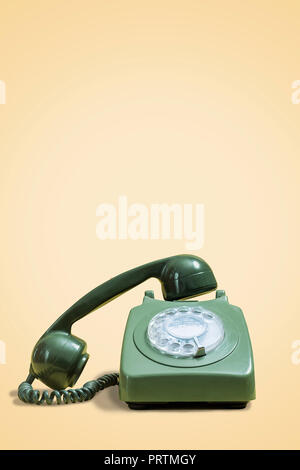 Verde vecchio telefono rotante su un vintage sfondo giallo con spazio per la copia e il testo Foto Stock