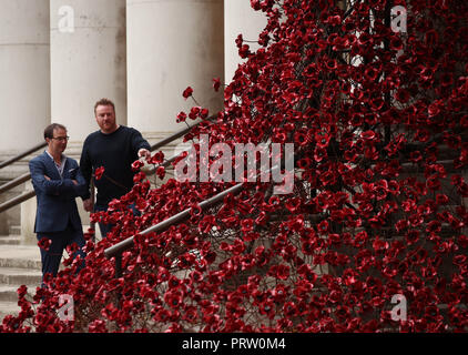 Solo uso editoriale designer Tom Piper (sinistra) e l'artista Paolo Cummins accanto a loro scultura di papavero piangendo finestra, dopo quattro anni di tour del Regno Unito si aprirà venerdì 5 ottobre presso l'Imperial War Museum di Londra. Foto Stock