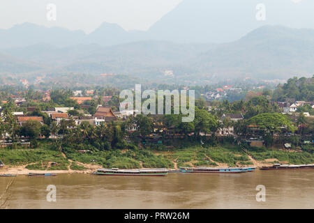 Ormeggiate barche sul fiume Mekong, città di Luang Prabang e montagne sullo sfondo visto dalla Chomphet District in una giornata di sole in Laos. Foto Stock