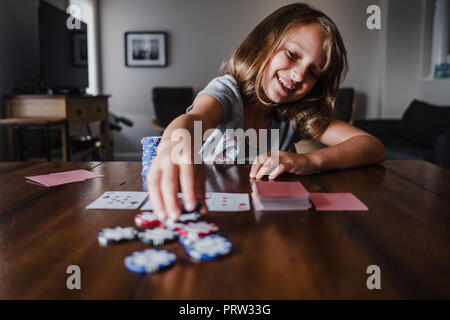 Ragazza giocando a carte in tavola, ponendo fiches Foto Stock