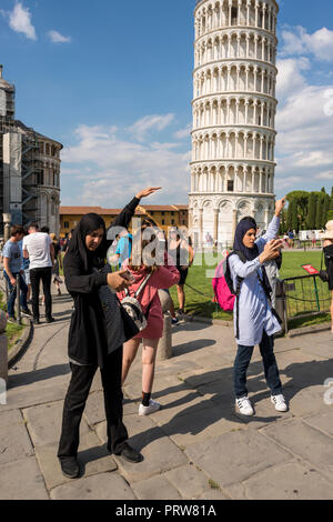 Due donne musulmane turisti tenendo selfie posa contro la Torre Pendente di Pisa, Toscana, Italia Foto Stock