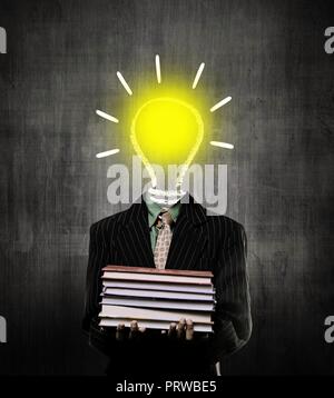 Le idee di accensione della lampadina e contenere libri e indossare tuta, mentre in piedi davanti a una lavagna Foto Stock