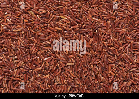 Asciugare il riso rosso sfondo. Non cotti food texture Foto Stock