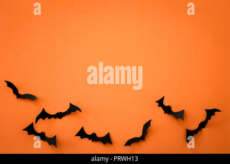 Flying carta nera pipistrelli su sfondo arancione. Halloween. Spazio di testo Foto Stock