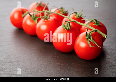 Rametto di pomodorini su grigio ardesia sfondo Foto Stock