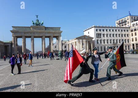 Giovane turista femminile in posa con American e soldato russo di fronte a Berlino o Gate Brandenburger Tor. Foto Stock