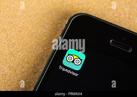 Mosca, Russia - 24 Luglio 2018: applicazione di Tripadvisor icona sulla schermata dello smartphone. Smartphone giace sulla sabbia. Solo uso editoriale. Foto Stock