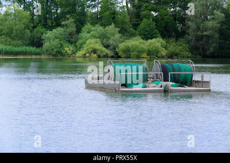 Industria attrezzatura di pesca con rete di laminati su un lago con la foresta in background Foto Stock