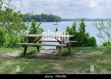 Luogo di picnic al Lago Costa - tranquillo scena di tavolo in legno con due panche presso la costa del lago Foto Stock