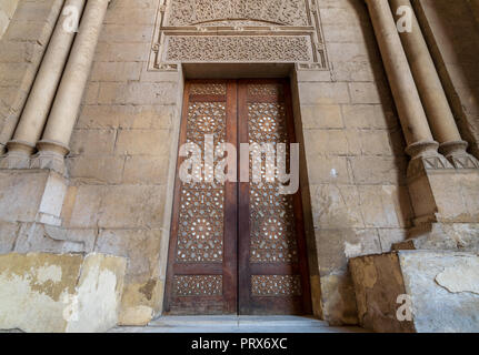 Vecchi esterna decorata mattoni muro di pietra con arabeschi decorata porta in legno incorniciata da pietra ornata di colonne cilindriche che conduce al Rifai moschea Foto Stock