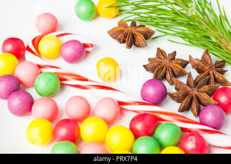 Closeup caramelle colorate con lecca-lecca, anice stellato e abete su sfondo bianco Foto Stock