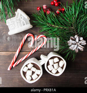 La cioccolata calda con marshmallow con casa di giocattoli e caramelle con albero di natale su sfondo di legno Foto Stock