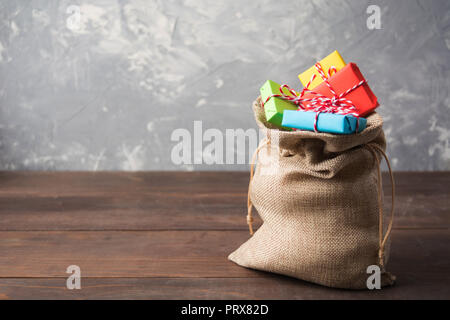 Babbo Natale borsa con doni colorati su un tavolo di legno con lo spazio di copia Foto Stock