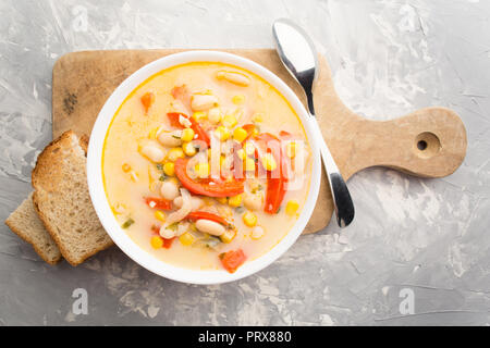 Minestra di crema con verdure e fagioli a bordo con il pane su uno sfondo grigio, vista aerea Foto Stock