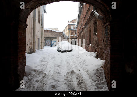 San Pietroburgo, Russia; - Gennaio 5, 2011: enormi ghiaccioli appesi da un tetto di un vecchio edificio; abbandonato auto coperto di neve Foto Stock