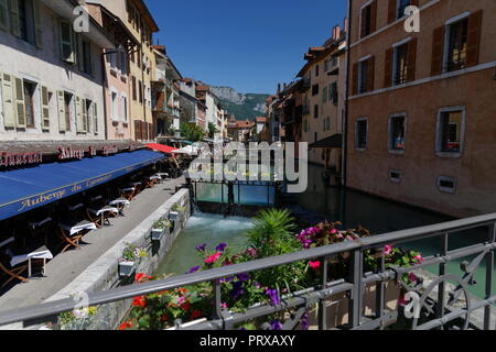 Negozi e caffetterie fiori e una wier sul canale di Annecy Francia Foto Stock