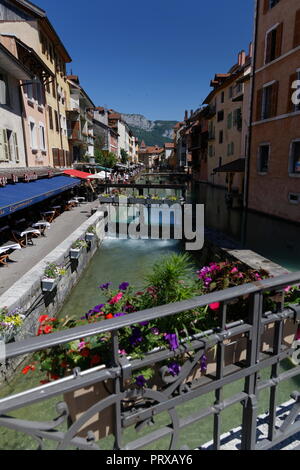 Negozi e caffetterie fiori e una wier sul canale di Annecy Francia Foto Stock