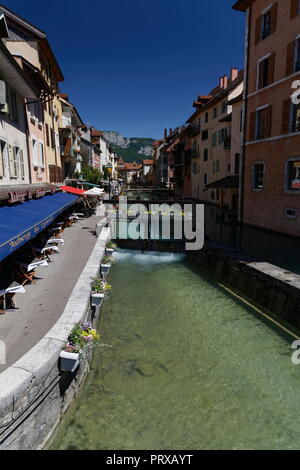 Negozi e caffetterie fiori e una wier sul canale di Annecy Francia Foto Stock