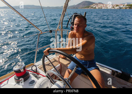 L'uomo corre skipper di una barca a vela sul mare. Foto Stock