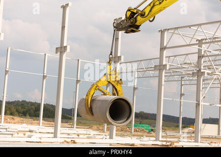 Sito in costruzione escavatore con un tubo di calcestruzzo Foto Stock